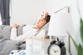 Sick Asian woman with cold sleeping on bed at home with high fever suffering from insomnia and medicine in foreground Royalty Free Stock Photo