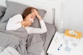 Sick Asian woman with cold sleeping on bed at home with high fever suffering from insomnia and medicine in foreground Royalty Free Stock Photo