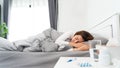 Sick Asian woman with cold sleeping on bed at home with high fever suffering from insomnia Royalty Free Stock Photo