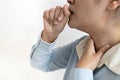 Sick asian woman with coughing into her fist and puts hand to her painful neck,sore throat,tonsillitis,symptom for cold,flu