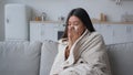 Sick Asian woman covered in blanket sneezing in paper napkin sneeze runny nose feel frozen cold unhealthy korean girl Royalty Free Stock Photo