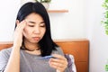 Sick Asian woman having headache from fever hand holding thermometer checking high temperature Royalty Free Stock Photo