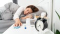 Sick Asian woman lying in bed take medicines pills and glass of water from bedside table to relieve symptoms Royalty Free Stock Photo