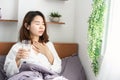 Sick Asian woman suffering from sore throat drinking water in her bed Royalty Free Stock Photo