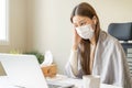 Sick asian young woman wearing mask wrapped blanket have headache have fever, flu and using laptop computer consulting with doctor Royalty Free Stock Photo