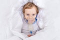 Sick baby boy with inhaler treats throat at home, the concept of health and inhalation treatment