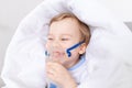 Sick baby boy with inhaler treats throat at home, the concept of health and inhalation treatment