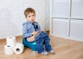 Child sitting on the potty with toilet paper. Colic, bloating, pain