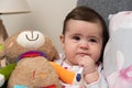 Sick baby girl with thermometer in mouth holding teddy bear Royalty Free Stock Photo