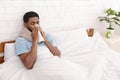 Young sick man in bed cleaning snotty nose Royalty Free Stock Photo