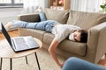 Sick bored woman with laptop lying on sofa at home Royalty Free Stock Photo