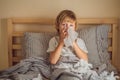 Sick boy coughs and wipes his nose with wipes. Sick child with fever and illness in bed Royalty Free Stock Photo