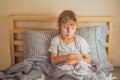 Sick boy coughs and wipes his nose with wipes. Sick child with fever and illness in bed Royalty Free Stock Photo