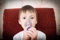 Sick boy in nebulizer mask making inhalation, respiratory procedure by pneumonia or cough for child, inhaler