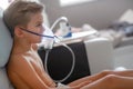 Sick boy in nebulizer mask making inhalation, respiratory procedure by pneumonia or cough for child, inhaler, compressor