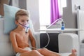 Sick boy in nebulizer mask making inhalation, respiratory procedure by pneumonia or cough for child, inhaler, compressor