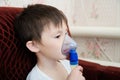 Sick boy in nebulizer mask making inhalation, respiratory procedure by pneumonia or cough for child, inhaler