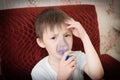 Sick boy in nebulizer mask making inhalation, respiratory procedure by pneumonia or cough for child