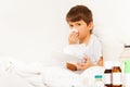 Sick boy sitting in bed and using paper napkins Royalty Free Stock Photo