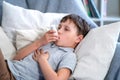Sick boy tired from chest coughing holding inhaler, having asthma using inhaler