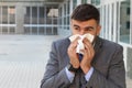 Sick businessman blowing his nose in office