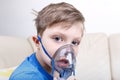 Sick chid with pediatric nebulizer looking at camera