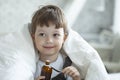 Sick child boy drinking cough syrup sitting on bed at home, children recover from flu