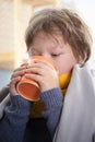 Sick child boy drinking hot tea to recover from flu. sitting in bed a at home