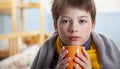 Sick child boy drinking hot tea to recover from flu. sitting in bed a at home Royalty Free Stock Photo