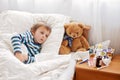 Sick child boy lying in bed with a fever, resting Royalty Free Stock Photo