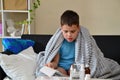 Sick child boy lying in bed with a fever, resting at home. a boy with a cold, treated. medicines, throat nose spray Royalty Free Stock Photo