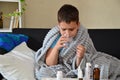 Sick child boy lying in bed with a fever, resting at home. a boy with a cold, treated. medicines, throat nose spray Royalty Free Stock Photo