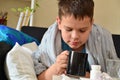 Sick child boy lying in bed with a fever, resting at home. a boy with a cold, treated. medicines, throat nose spray Royalty Free Stock Photo