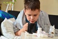 Sick child boy lying in bed with a fever, resting at home. a boy with a cold, treated. medicines, throat nose spray Royalty Free Stock Photo