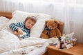 Sick child boy lying in bed with a fever, resting Royalty Free Stock Photo