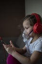 Sick child caucasian girl with cough and virus wearing nebulizer mask playing mobile phone and red headphones