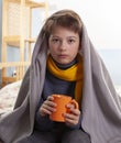 Sick child sitting on bed a at home boy drinking hot tea to recover from flu Royalty Free Stock Photo