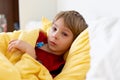 Sick child, toddler boy lying in bed with a fever, having breakfast, resting at home Royalty Free Stock Photo