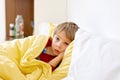 Sick child, toddler boy lying in bed with a fever, having breakfast, resting at home Royalty Free Stock Photo