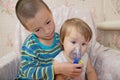 Sick children - boy make nebulizer mask for inhalation for little sister, respiratory procedure by pneumonia or cough for child