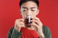 Sick cold and headache Young Asian man wearing a sweater while drinking hot tea