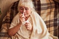 Senior woman with flu using nasal spray at home Royalty Free Stock Photo