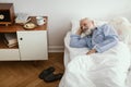 Sick elderly man wearing blue pajama lying in bed at nursing home