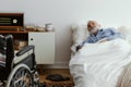 Sick elderly man wearing blue pajama lying in bed at nursing home Royalty Free Stock Photo