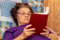 Sick elderly woman lying on the couch and reading a book. Reading the Bible Royalty Free Stock Photo