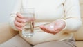 Sick elderly woman and medication, healthcare. Close-up of ill pensioner's hand holding two capsules of medicine, painkiller