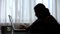 Sick female freelancer working on laptop early in morning and drinking tea