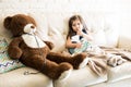 Sick girl with doctor teddy bear on sofa Royalty Free Stock Photo