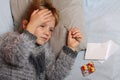 Sick girl lying in bed with a thermometer and medicine. Child winter flu allergy health care concept Royalty Free Stock Photo