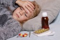 Sick girl lying in bed with a thermometer and medicine. Child winter flu allergy health care concept Royalty Free Stock Photo